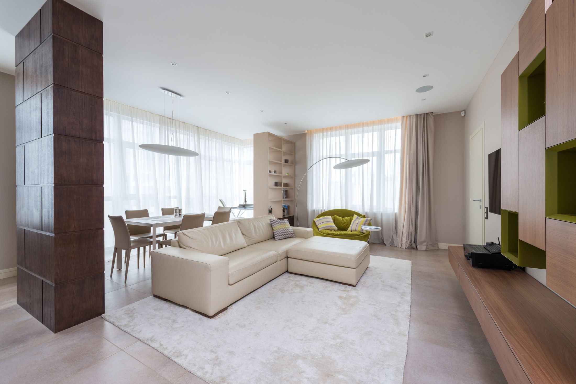 Un appartement lumineux avec canapé blanc, grandes fenêtres et espace salle à manger